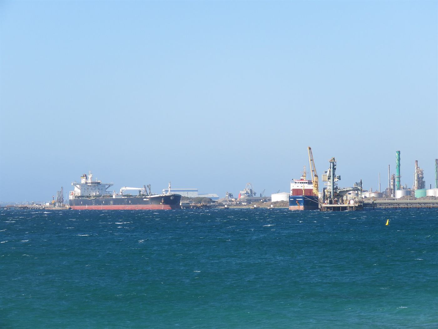 A crude oil tanker at a refinery jetty, the vessel class whose insurance repriced.